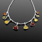 Trio of citrine green and cognac Baltic amber triangular charms close up