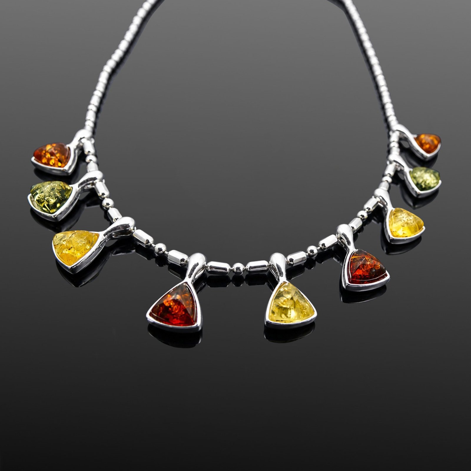 Trio of citrine green and cognac Baltic amber triangular charms close up