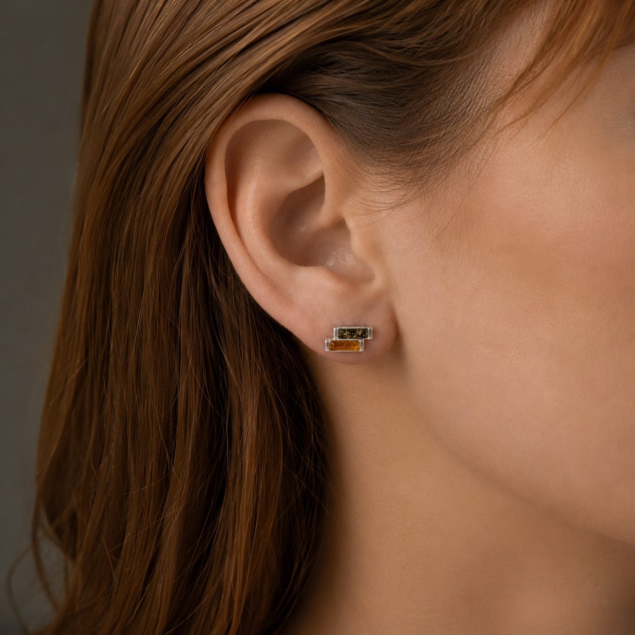 Contemporary amber stud earrings worn close to ear two tone modern design