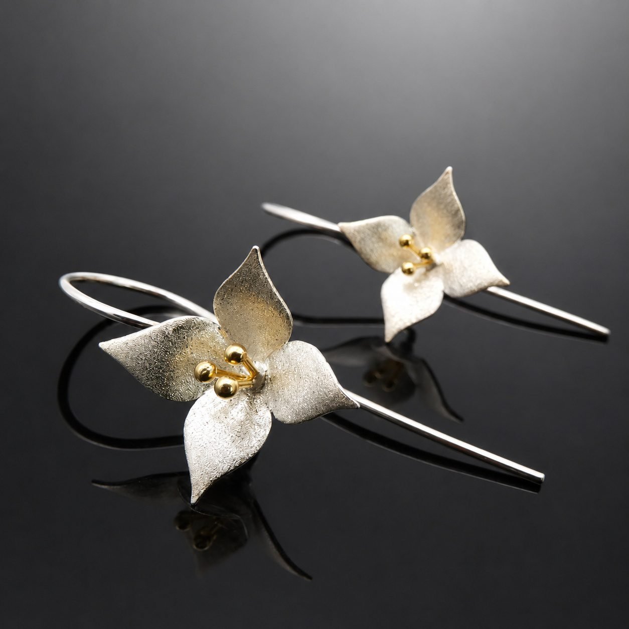 Satin finish sterling silver four petal blossom with gold stem detail earring 28mm close up